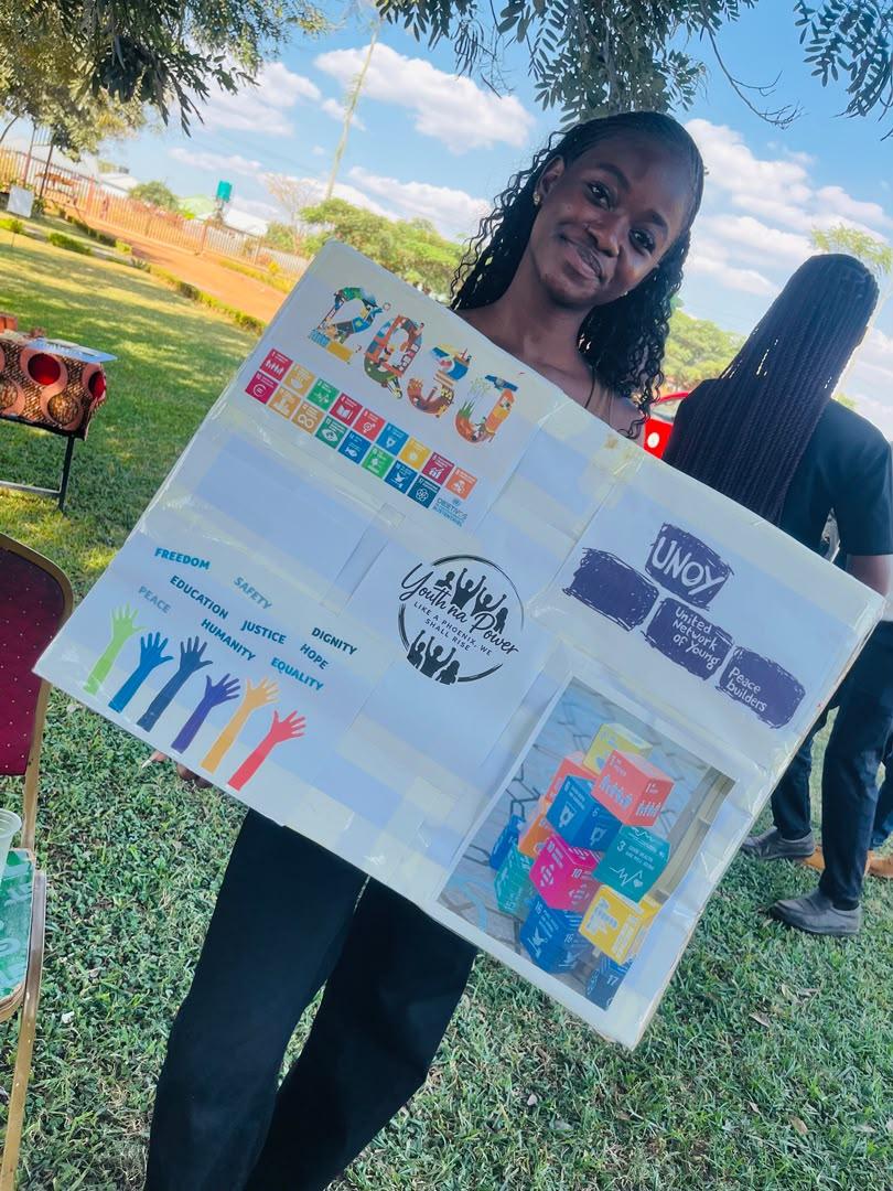 A young member smiling while presenting a hand-made 2030 goals poster