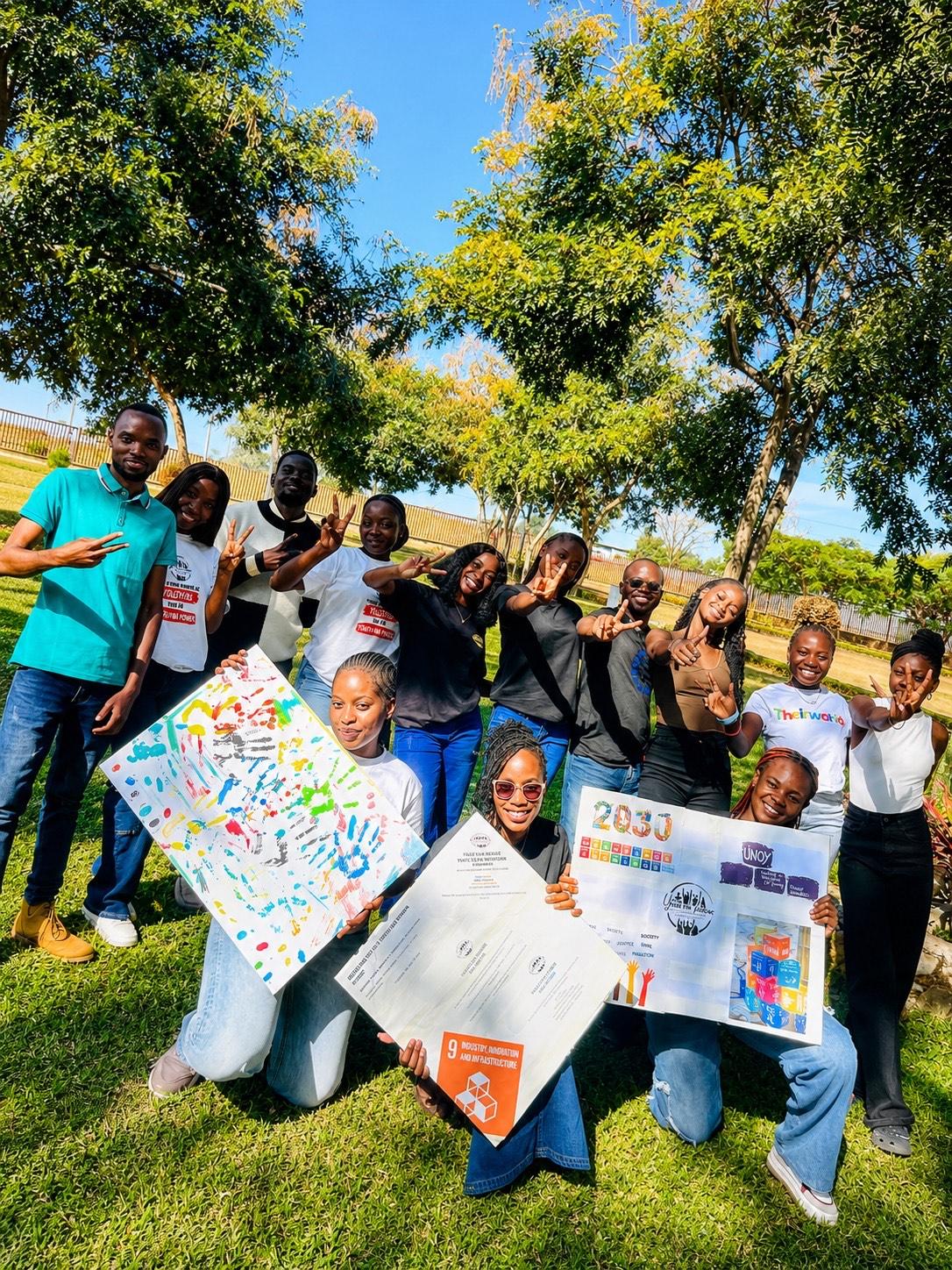 Youth Na Power members wearing branded shirts, holding posters at an outdoor gathering in Ndola